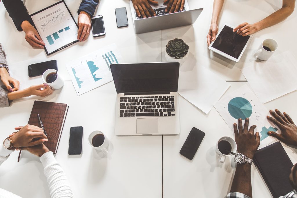 top view work workplace. a team of young office workers, businessmen with laptop working at the table, communicating together in an office. corporate businessteam and manager in a meeting. coworking. top view work workplace. a team of young office workers, businessmen with laptop working at the table, communicating together in an office. corporate businessteam and manager in a meeting. coworking.